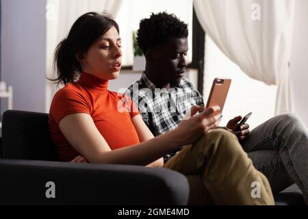 Nahaufnahme von modernen interracial paar mit Smartphones zu Hause. Liebhaber multiethnischer Herkunft, die digitale Geräte mit Technologie halten. Multirassische Menschen mit Gadgets mit Online-Internet. Stockfoto