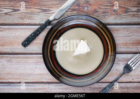 Frischer Käse auf einem Teller von auf hölzernem Hintergrund. Stockfoto