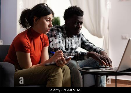 Interracial paar Berechnung Steuergeld mit Laptop für Wirtschaft und Budget. Verheiratet multi ethnischen Liebhaber mit Notebook tun Steuern und Finanzbuchhaltung, Überprüfung Online-Zahlung Stockfoto