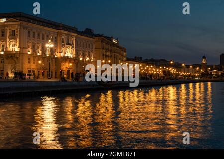 Küste in Triest Italien mit schönen beleuchteten Gebäuden und Reflexion auf dem Wasser. Stockfoto