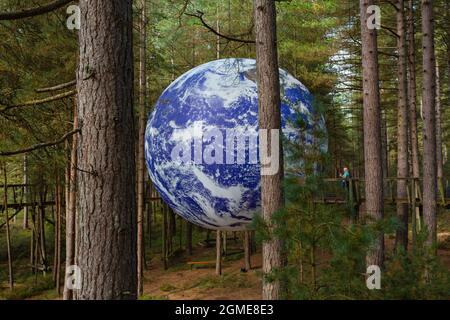 Moors Valley Park, Nr Ringwood, Hampshire, Großbritannien. September 2021. Besucher sehen Luke Jerrams Gaia unter den Bäumen im Moors Valley Country Park & Forest, Nr Ringwood, Hampshire. Gaia, d.h. die Personifizierung der Erde misst 7 Meter im Durchmesser. Die Veranstaltung ist Teil der Inside Out Dorset Activate Performing Arts. Quelle: Carolyn Jenkins/Alamy Live News Stockfoto