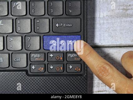 Konzept von Frage und Antwort. Q und Eine Online-Unterstützung. Fingerdruck auf eine blaue Taste mit der Bezeichnung Q und A mit Symbol auf einem Computertastaturkonzept Stockfoto