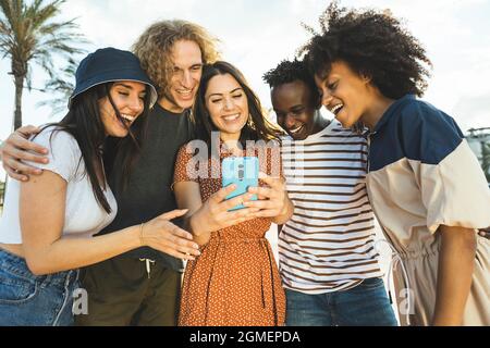 Multirassische Gruppe junger Menschen, die auf der Straße auf das Smartphone schauen. Stockfoto