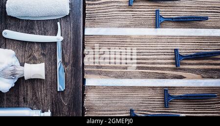 Rasierzubehör auf einem Hintergrund mit Holzstruktur. Werkzeuge. Einweg-Rasierer, Bürste, Rasierer mit Schaumgefahr. Stockfoto