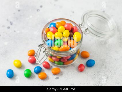 Verschiedene süße Bonbons aus Milchschokolade mit Reiscenter in einer Zuckerschale im Glasgefäß auf einem hellen Tisch. Draufsicht Stockfoto