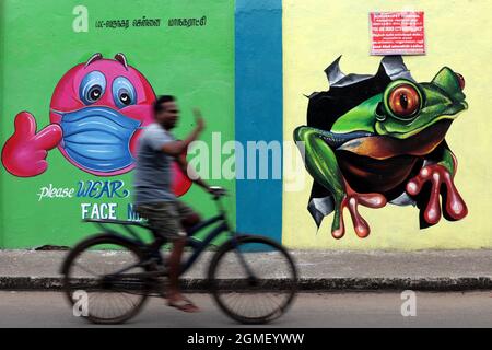 Chennai, Tamil Nadu, Indien. September 2021. Ein Mann fährt mit dem Fahrrad an einem Covid-19 Coronavirus-Bewusstseinsbild entlang des Straßenrands in Chennai vorbei. (Bild: © Sri Loganathan/ZUMA Press Wire) Stockfoto