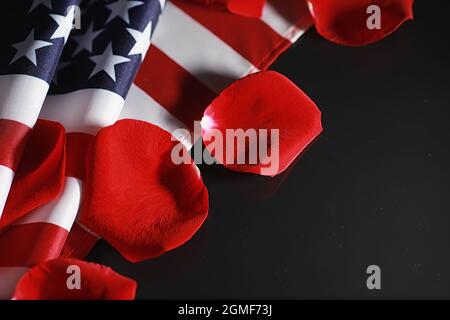 Amerikanische Flagge und Rosenblume auf dem Tisch. Symbol der Vereinigten Staaten von Amerika und rote Blütenblätter. Patriotismus und Erinnerung. Stockfoto