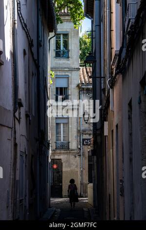 Silhouette einer Frau, die die Rue Bon Martinet in Avignon, Frankreich, hinuntergeht. Stockfoto