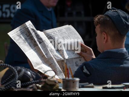 IWM Duxford, Cambridgeshire, Großbritannien. 18. September 2021. Die Battle of Britain Air Show findet am 18-19. September im Imperial war Museum IWM Duxford statt, Der ehemalige RAF-Standort, der in einigen der dramatischsten Tage der Geschichte des 20. Jahrhunderts eine zentrale Rolle spielte - als Stützpunkt für viele der Spitfire- und hurribepiloten während des Zweiten Weltkriegs - mit der Airshow mit gespielten Darstellern aus den 1940er Jahren. Ein RAF-Pilot in Uniform des 2. Weltkriegs liest die Nachrichten auf der Titelseite der Daity Express-Zeitung vom 12 1940. September. Quelle: Malcolm Park/Alamy Live News Stockfoto