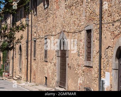 Außenmauer mit Türen und Fenstern eines antiken Hauses im italienischen mittelalterlichen Dorf Bolgheri in der Toskana. Stockfoto