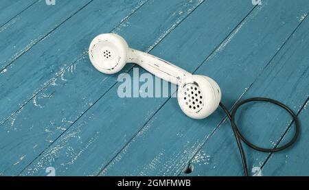 Weißes Hörer Vintage-Telefon auf einem Retro-alten blauen Holz texturierten Plank Hintergrund Stockfoto