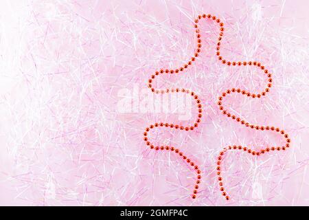 Symbol Weihnachten und Happy New Year Figur weihnachtsbaum mit roten Perlen auf Lametta. Weihnachtsperlen auf rosa Lametta. Urlaubskonzept. Draufsicht Stockfoto