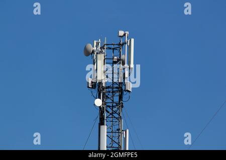 Handy-Turm vor dem Hintergrund eines blauen Himmels und einer weißen Wolke. Fernsehturm für Telekommunikation. Mobilfunkantenne. Wi-Fi-Sender Stockfoto