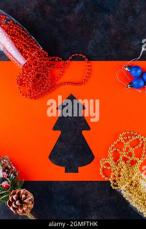Sektgläser mit Weihnachtsperlen auf dunklem Hintergrund. Weihnachtskugeln, bunte Perlen und Fichtenzweig. Papiergeschnittener weihnachtsbaum. Draufsicht Stockfoto
