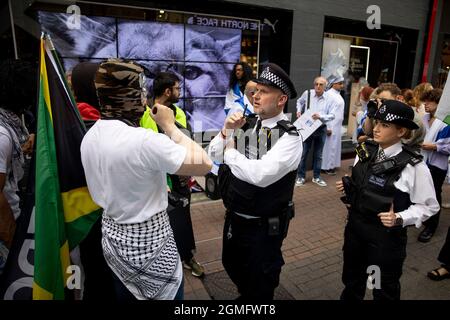 London, Großbritannien. September 2021. Während der Demonstration konfrontierte ein Protestierender einen Polizisten in der Carnaby Street.Eine globale Boykottkampagne, die von palästinensischen Anhängern gegen Puma zur Überprüfung ihrer Unterstützung des israelischen Fußballverbands aufgerufen wurde. Eine kleine Gruppe von Gegendemonstlern, die Israelis unterstützen, präsentierte sich bei der Boykott-Aktion vor dem Flagship-Store von Puma in London. Kredit: SOPA Images Limited/Alamy Live Nachrichten Stockfoto