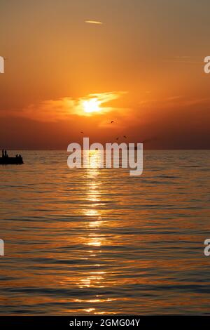 Sonnenuntergang in triest mit Silhouette von Vogelfischen und Menschen auf dem Pier . Stockfoto