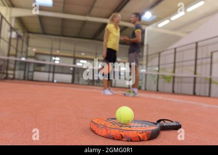 Tennisschläger und Ball im Vordergrund sprechen im Hintergrund Stockfoto