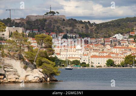 Sibenik, Kroatien - 25. August 2021: Altes Haus mit Hafen, Promenade, Steinhäusern, Kathedrale und Festung, die vom Meer aus gesehen wird, wenn man mit dem Schiff ankommt Stockfoto