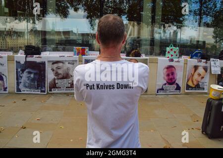 London, Großbritannien. September 2021. Vor dem New Scotland Yard steht ein Aktivist neben Bildern von Opfern von Messerverbrechen während der Demonstration „Binning Knives rves Lives“. Kredit: Vuk Valcic / Alamy Live Nachrichten Stockfoto