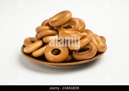 Auf einer braunen Keramikuntertasse liegt ein Stapel Bagels auf weißem Hintergrund zur Korrektur Stockfoto