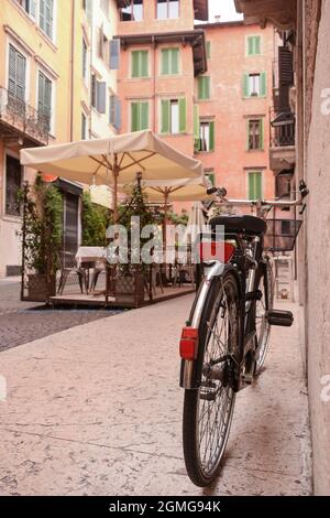 In der Nähe des Eingangs zum alten Haus, im alten Viertel der Stadt, gibt es ein Fahrrad mit einem Korb für den Transport von Lebensmitteln in der Nähe der Wand. Stockfoto