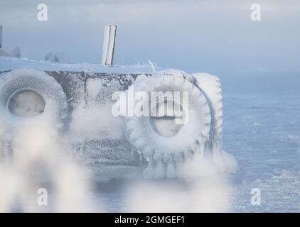 Eisbedeckte Bootsanlegestellen mit Traktorrädern an der Ostsee in Helsinki, Finnland. Stockfoto