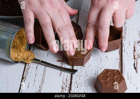 Konditor, der einen kleinen brasilianischen Honigkuchen fertig stellt, neben einer Dose Dulce de leche. Stockfoto