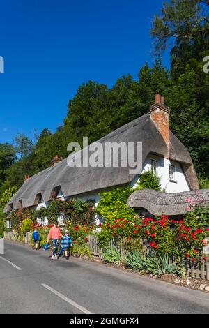 England, Hampshire, Test Valley, Wherwell, traditionelles Reetgedeckten Country House und Empty Road Stockfoto