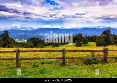 Holzzaun um grasende Farm tief in Dorrigo Stadt Hochland Land Hochplateau, NSW, Australien - fernen Regensturm über Dorrigo Berge. Stockfoto