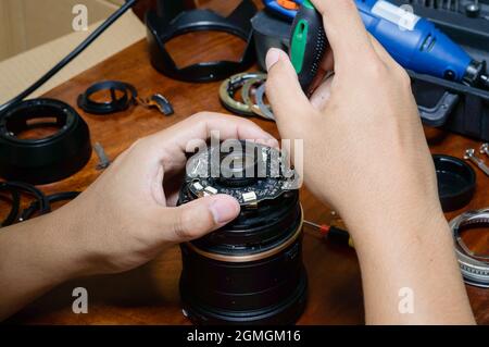 Zwei Hände eines Mannes, der das Objektiv einer Kamera machte, reparierten Stockfoto