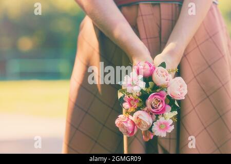 Kaukasisches Mädchen, das einen Blumenstrauß in den Händen auf dem Hintergrund eines grünen Sommersonnentages hält. Hochwertige Fotos Stockfoto