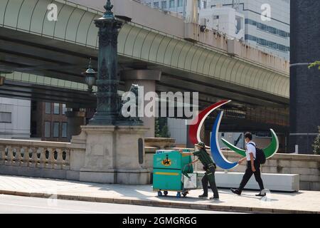 Während der Paralympics in Tokio passieren Menschen, darunter ein Yamato-Zustellarbeiter, an einer Löwenstatue auf der Nihonbashi-Brücke ein Paralympisches Symbol-Denkmal. Stockfoto