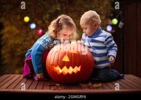 Kind schnitzt Halloween Kürbis. Kinder schnitzen Kürbisse für Trick or Treat Jack o Laterne. Herbstaktivitäten für Kinder. Stockfoto