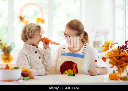 Familie kocht Thanksgiving-Abendessen Großmutter und Kind schnitten Kürbis in der dekorierten Küche. Mutter und Kind kochen im Herbst Gemüse. Stockfoto