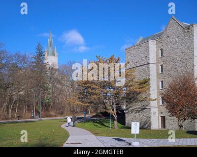 London, Ontario, Kanada - 4. Dezember 2018: Studenten wandern auf dem Campus der Western University in Richtung des Middlesex College-Uhrturms. Stockfoto