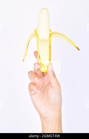 Geschälte Banane in der Frauenhand auf weißem Hintergrund Stockfoto