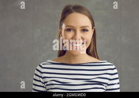 Headshot Porträt von jungen toothy lächelnden Frau auf grauen Studio-Hintergrund Stockfoto