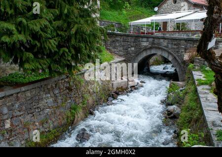 Rila Bulgarien, Bach durch Bergdorf mit Steinbrücke Stockfoto