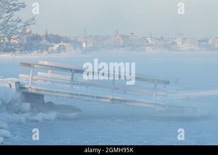 Eisbedeckte schwimmende Pontonladerampe mit an der eisigen Ostsee in Helsinki, Finnland. Stockfoto