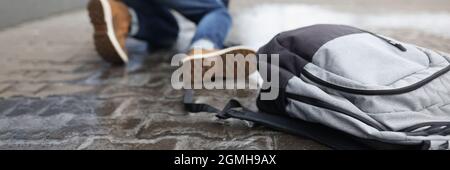 Mann mit Rucksack, der in der Nähe des Winters auf rutschigem Bürgersteig fällte Stockfoto