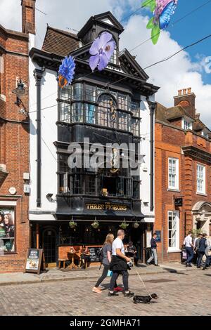 The Three Pigeons Pub in der Guildford High Street, Surrey, Großbritannien, mit Leuten, die vorbeilaufen und Trinkern, die an einem sonnigen Tag draußen sitzen Stockfoto
