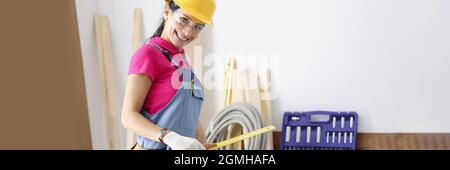 Frau Baumeisterin in Schutzhelm und Overalls halten Herrscher in den Händen Stockfoto