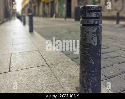 Alte Straße in Madrid mit Pflastersteinpflaster und Pollern, die den Bürgersteig von der Straße trennen. Stockfoto