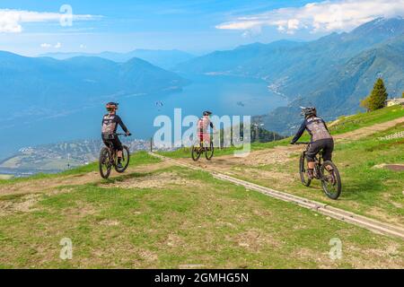 Verzasca, Schweiz - Juni 2021: Mountainbiker fahren vom Gipfel des Cardada-Cimetta-Gebirges in der Schweiz herunter. Schweizer Sessellift Skyline Stockfoto