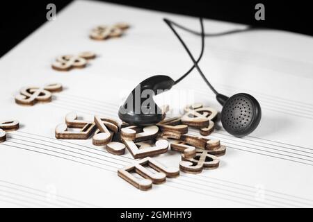 Mit schwarzen Kopfhörern häufen sich hölzerne Musiknoten. Stockfoto