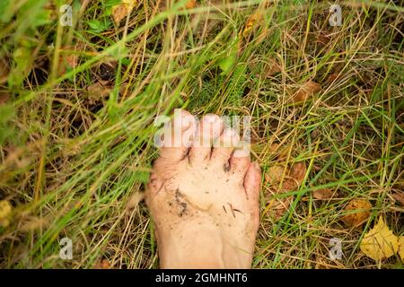 Frauenfuß ist mit Schlamm auf dem Gras bedeckt Stockfoto