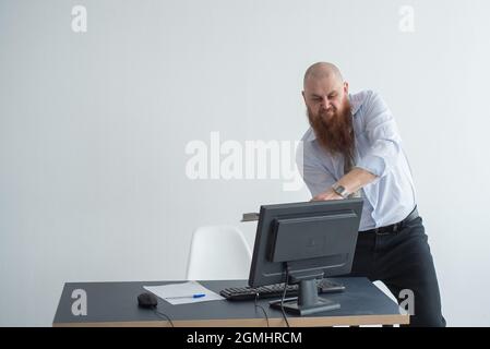 Gestresste verrückte Geschäftsmann zerschlagen seinen Computer im Büro mit Axt Problem Konzept. Der Mann hat Probleme bei der Arbeit und Frustration. Stockfoto