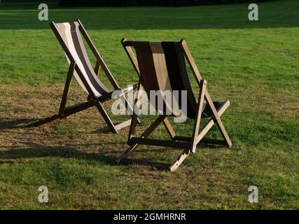 Zwei leere Liegestühle auf Gras bei Abendsonne mit Schatten Stockfoto