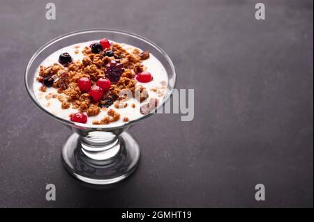 Tasse frischer Joghurt mit Müsli und Obst auf grauem Hintergrund Stockfoto