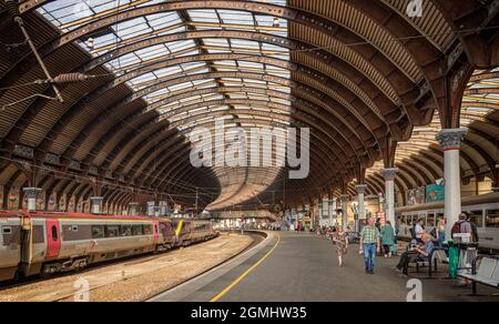 Ein Panorama einer Bahnhofskonkurse. Ein eiserner Baldachin aus dem 18. Jahrhundert mit einem Dachfenster, das sich über den Plattformen schlängelt. Züge warten auf Bahnsteigen. Stockfoto